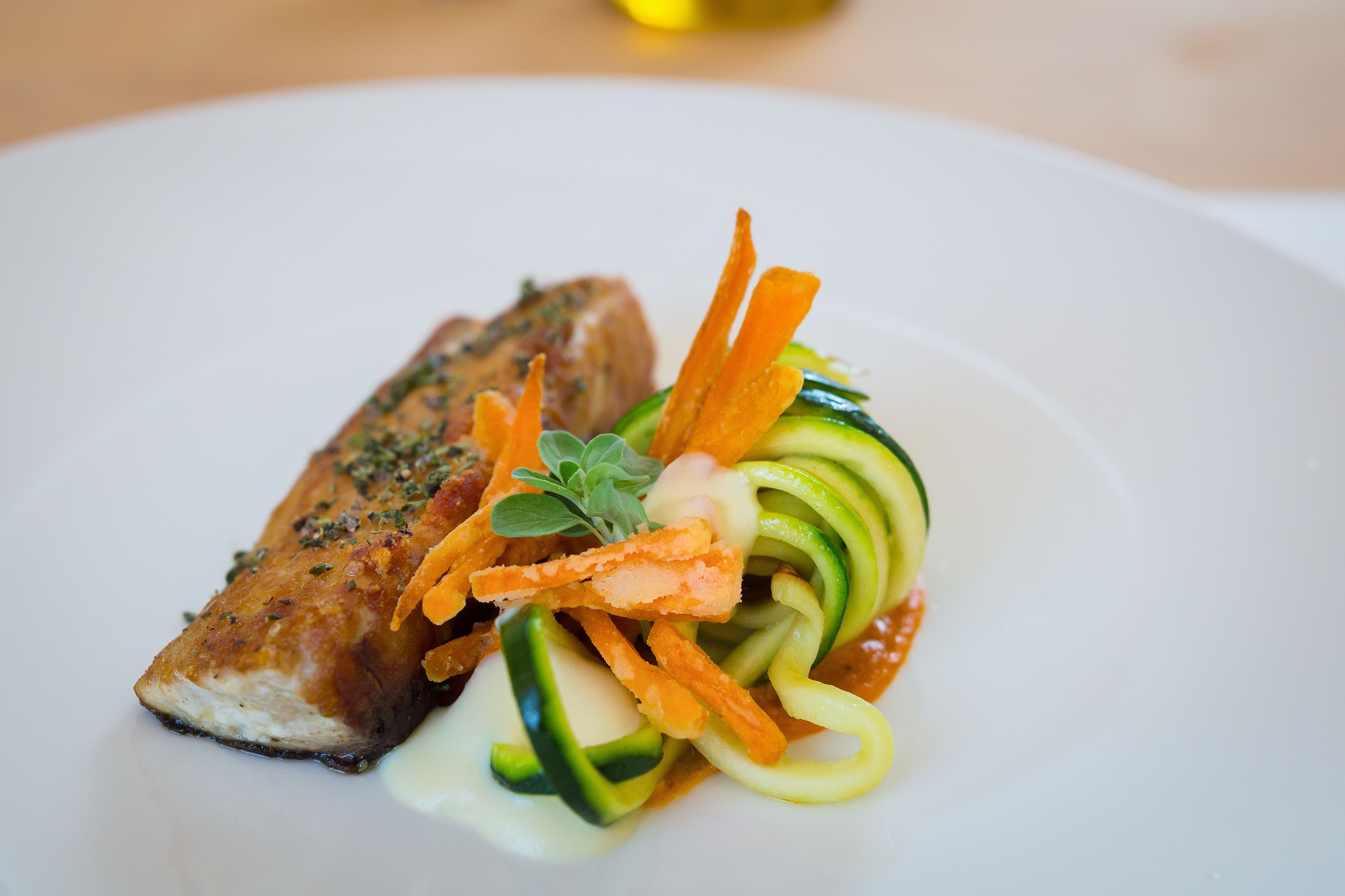 Un plato con un trozo de pescado y una ensalada de verduras.