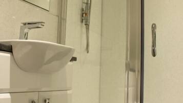 A modern bathroom with a glass-enclosed shower, a white sink, and a mirror above the vanity.
