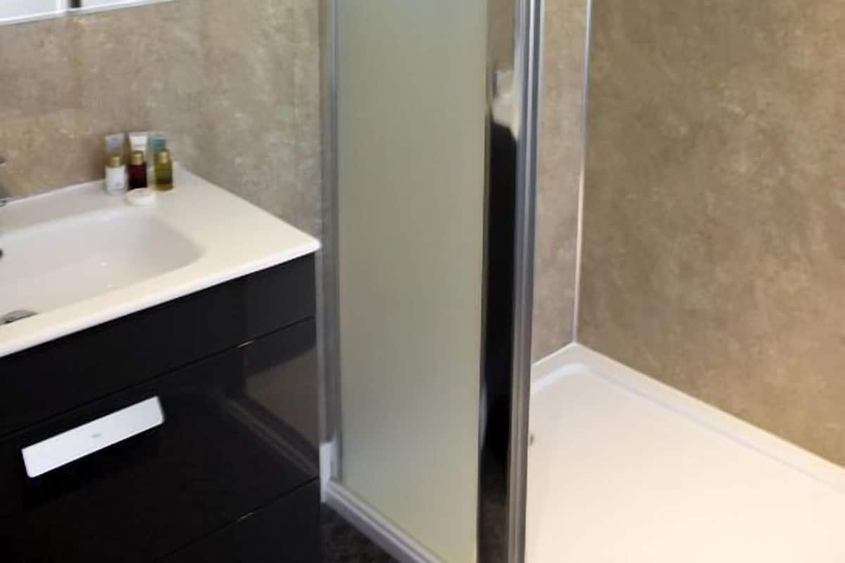 A modern bathroom with a glass shower enclosure, a white sink, and a mirror.