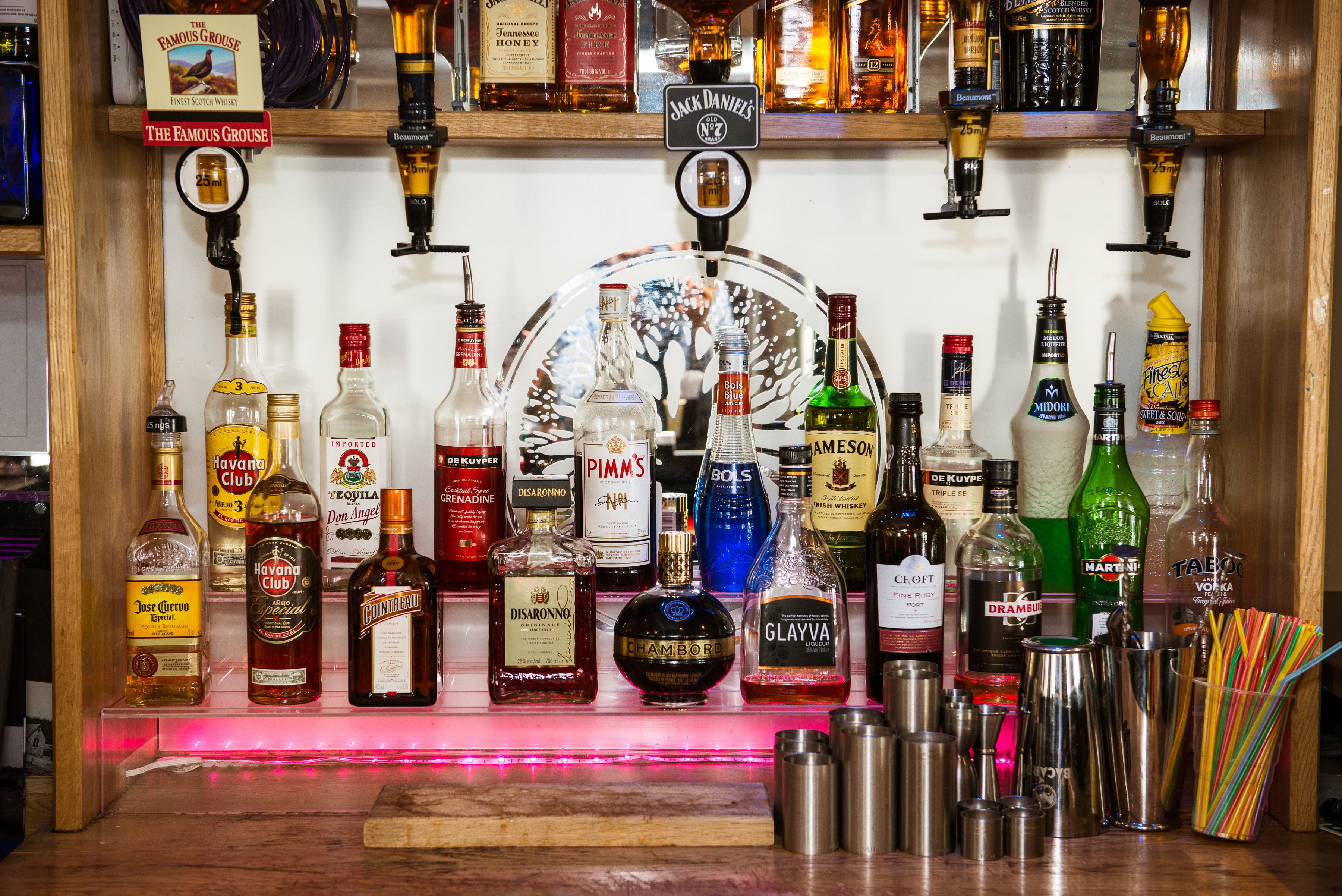 Een bar met verschillende drankflessen en een groot rond bord.