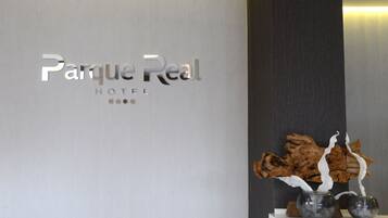 A hotel sign with the name 'Parque Real Hotel' and a decorative vase with branches on a shelf.