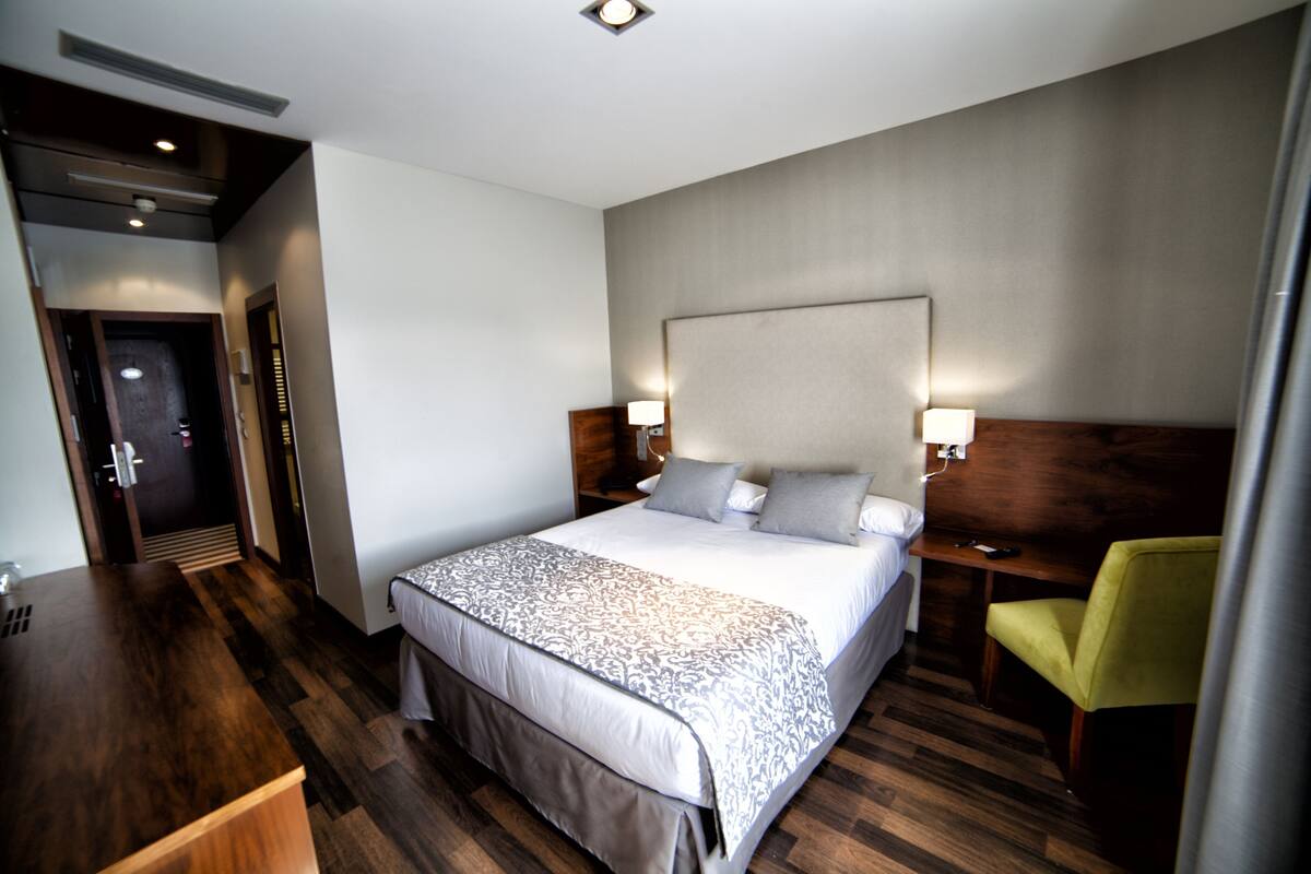 A hotel room with a large bed, bedside tables, a desk, and a chair.