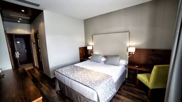A hotel room with a large bed, bedside tables, a desk, and a chair.