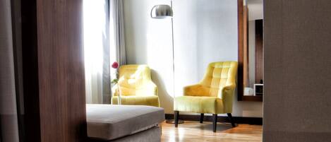 A modern living room with a sofa, two armchairs, a floor lamp, and a wooden floor.