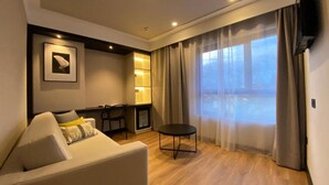 Un salon moderne avec un canapé, une petite table et une vue sur l’extérieur grâce à de grandes fenêtres.