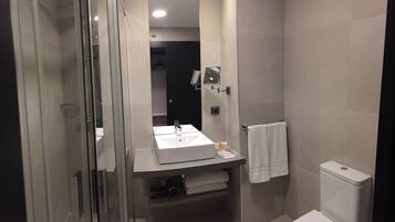 Une salle de bain moderne avec une douche à parois de verre, un lavabo blanc et des toilettes.