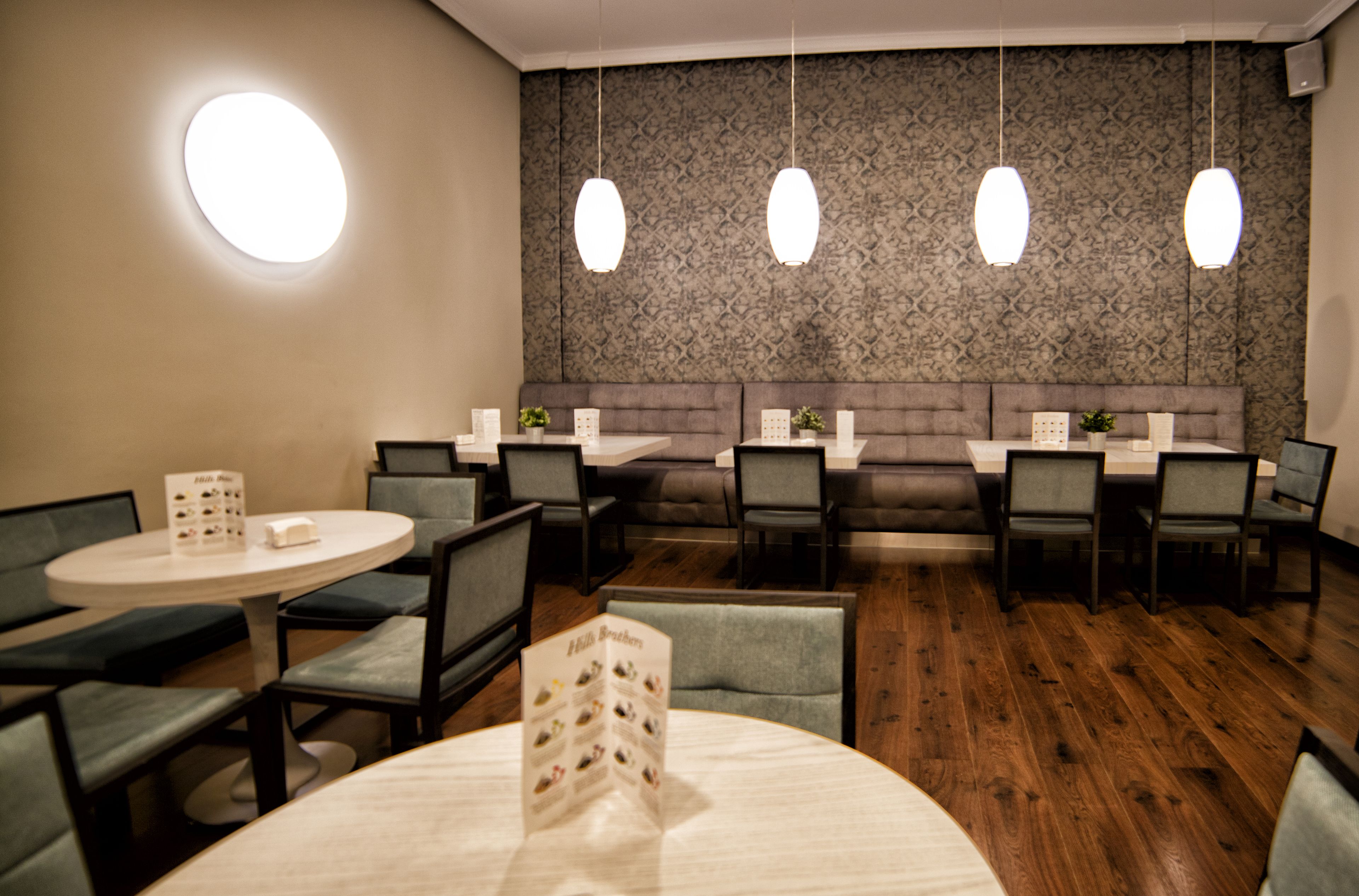 Un restaurante con mesas redondas, cabinas y lámparas colgantes.