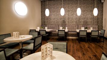 Un restaurante con mesas redondas, cabinas y lámparas colgantes.