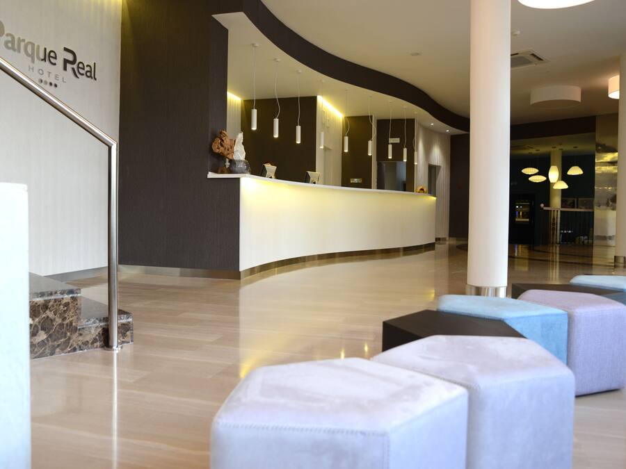 A modern hotel reception area with a curved reception desk, marble steps, and plush seating.