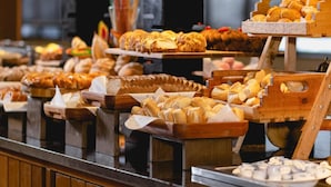 A variety of baked goods displayed on wooden stands in a bakery setting. - Mendes Plaza Hotel Torre Panorama (Santos)