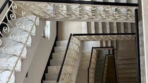 A modern staircase with a black handrail and decorative white railings. - La Balnearia (Alassio)