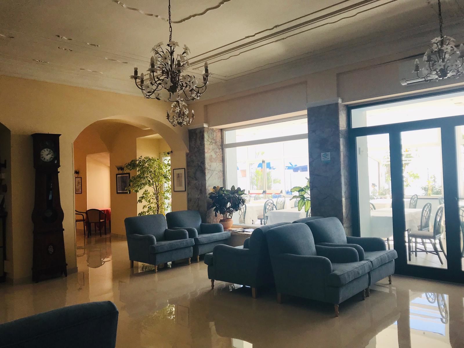Eine geräumige Lobby mit einer Kandelaber, bequemen Sitzgelegenheiten und großen Fenstern mit Blick nach außen.