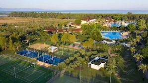 Vue aérienne d’un complexe hôtelier doté d’une grande piscine, de courts de tennis et offrant une vue panoramique sur l’océan.