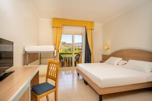 Habitación de hotel con cama, escritorio, silla, televisor y balcón con vistas.