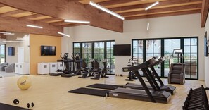 Een fitnessruimte met trainingsapparatuur, een yogabal en een televisie aan de muur.