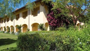 Un edificio con múltiples ventanales arqueados y un jardín con diversas plantas y flores.