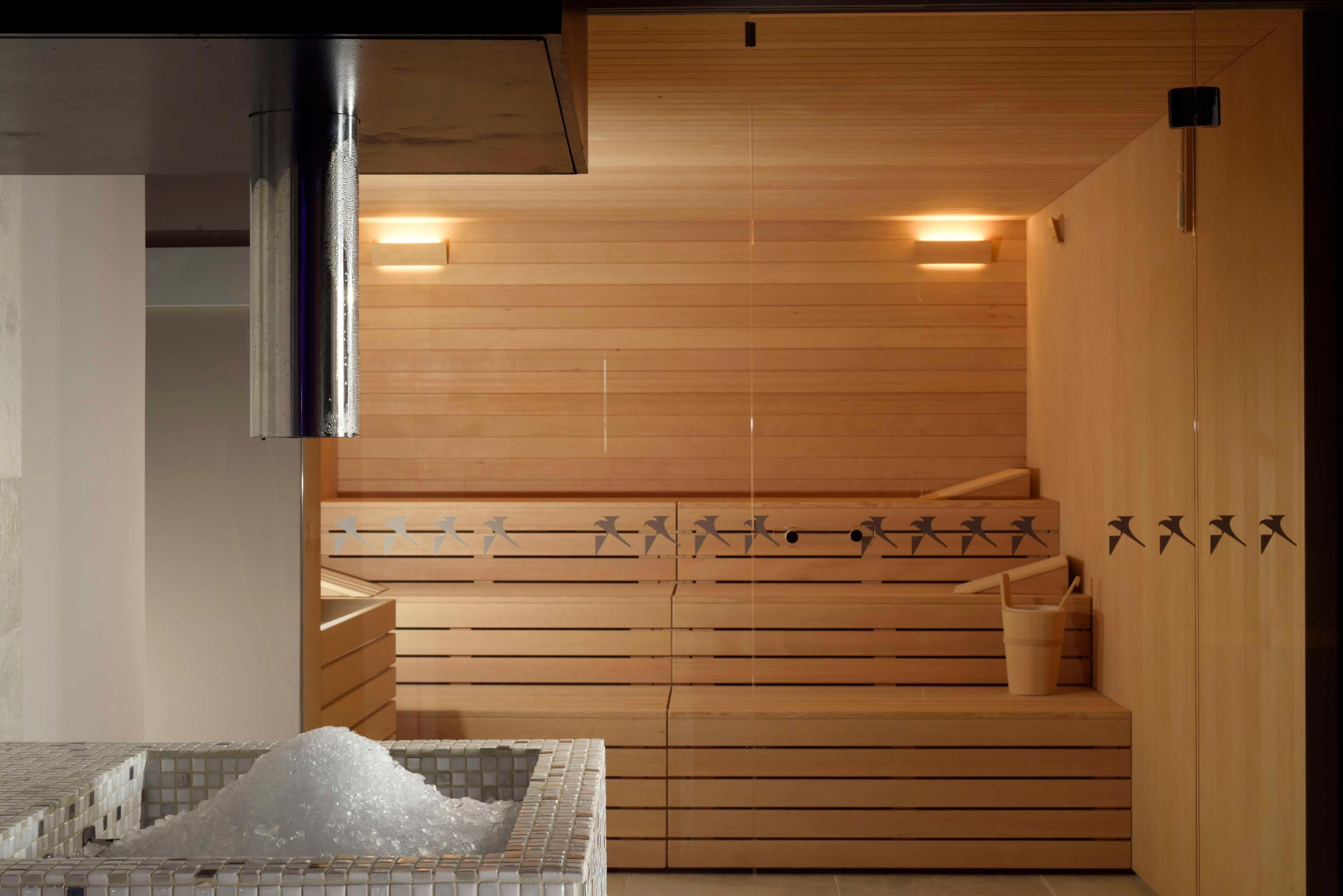 Una sauna amb bancs de fusta, terra de rajola i un cubell.