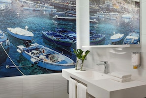 A bathroom with a large mural of boats, a white sink, a towel rack, and a soap dispenser. - Falkensteiner Club Funimation Garden Calabria (Curinga)