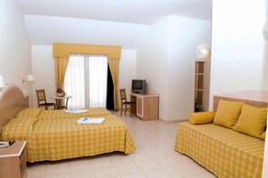Habitación de hotel con dos camas, un escritorio, un televisor y una pequeña mesa con sillas.