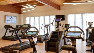 A gym with treadmills, ellipticals, and a TV screen.