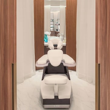 A modern bathroom with a central sink, mirror, and a massage chair.