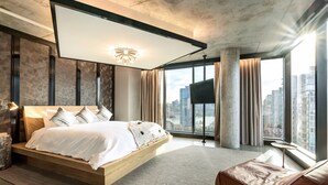 A modern bedroom with a large bed, a TV, and a city view. - the DOUGLAS, Autograph Collection (Vancouver)