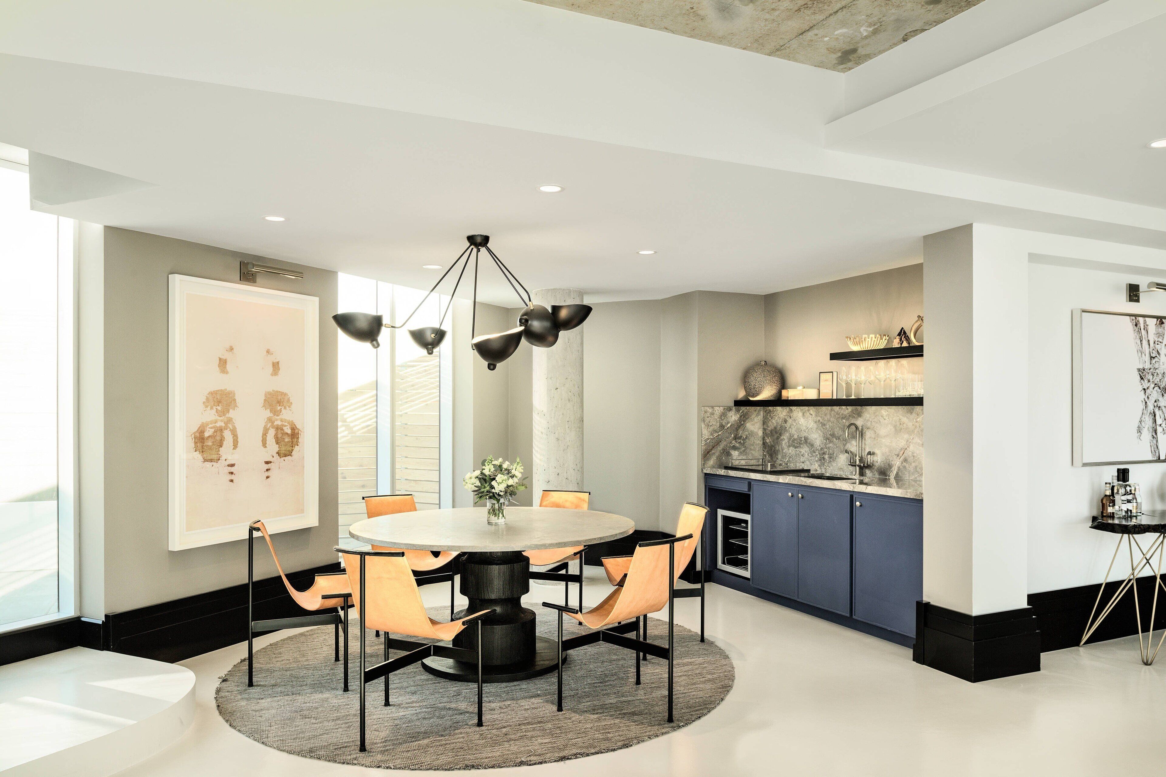 A modern kitchen with a round dining table, pendant lighting, and a view of the city.