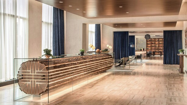 A modern reception area with a central counter, seating, and a view of the reception desk. - the DOUGLAS, Autograph Collection (Vancouver)