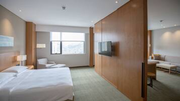 A hotel room with a bed, a desk, a chair, a TV, and a large window.