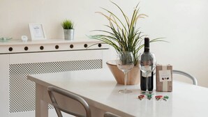 Una cocina moderna con encimera blanca, una planta en maceta, una botella de vino y una copa de vino.