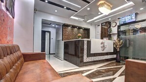 Um lobby de hotel moderno com uma receção, um sofá de couro castanho e um chão estampado.
