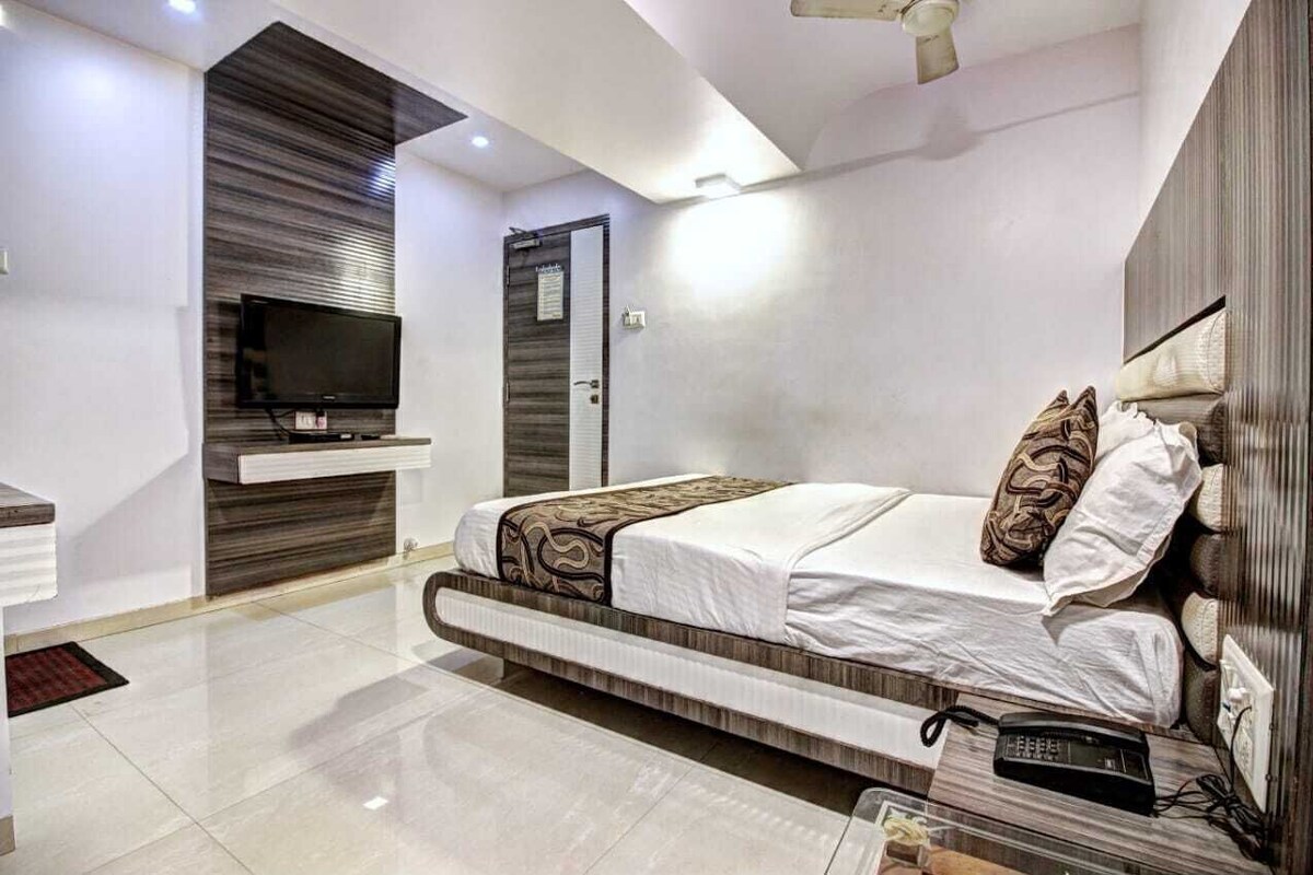 A modern bedroom with a bed, a television, and a bedside table.