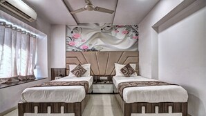 Quarto com duas camas, ventoinha no teto, parede decorativa e janela com cortinas.