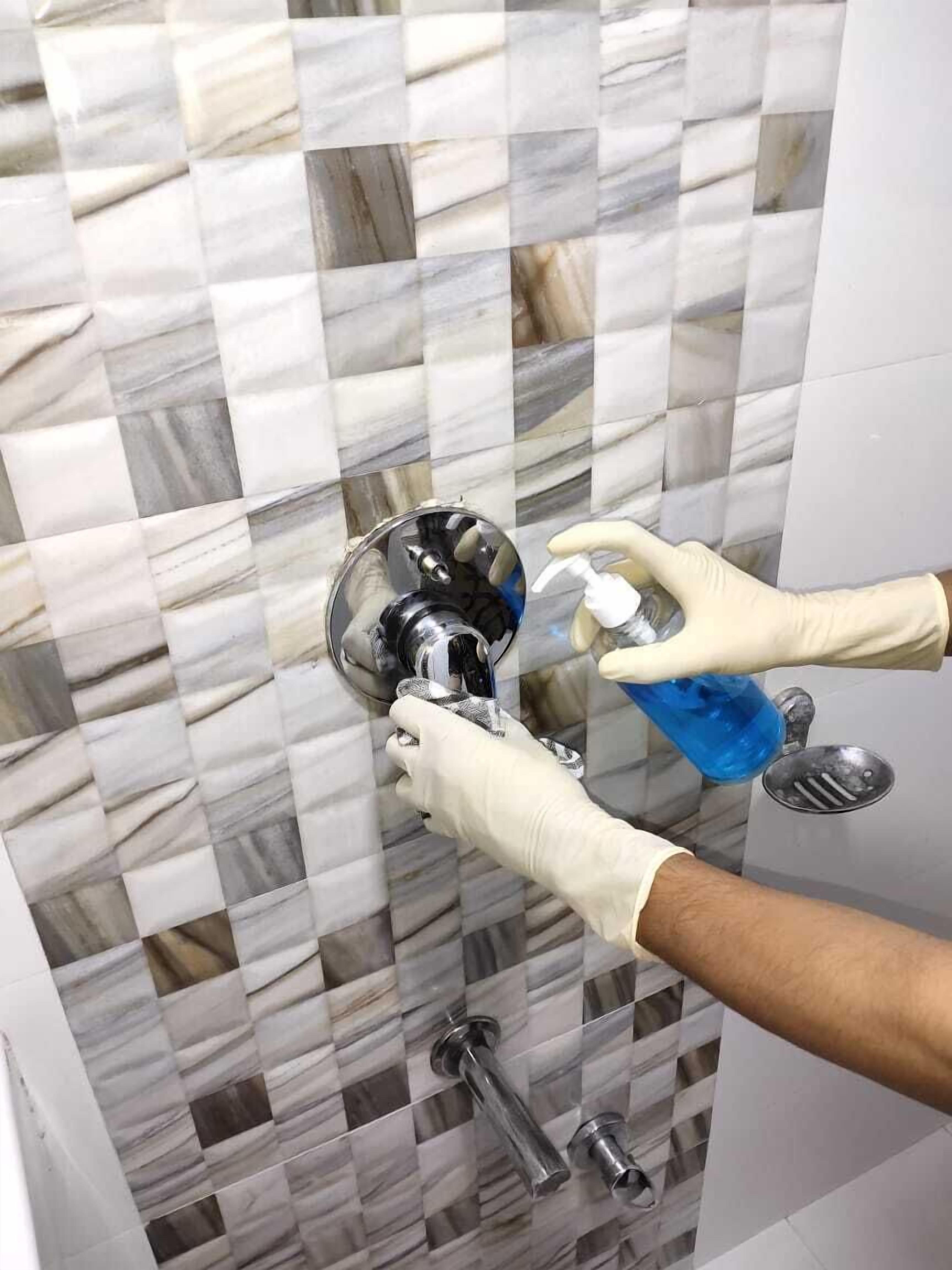 Un baño con pared de mármol con baldosas en damero y zona de ducha con ducha de mano.