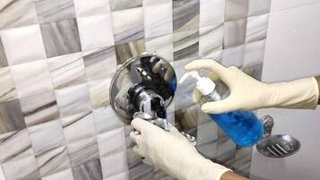 Un baño con pared de mármol con baldosas en damero y zona de ducha con ducha de mano.