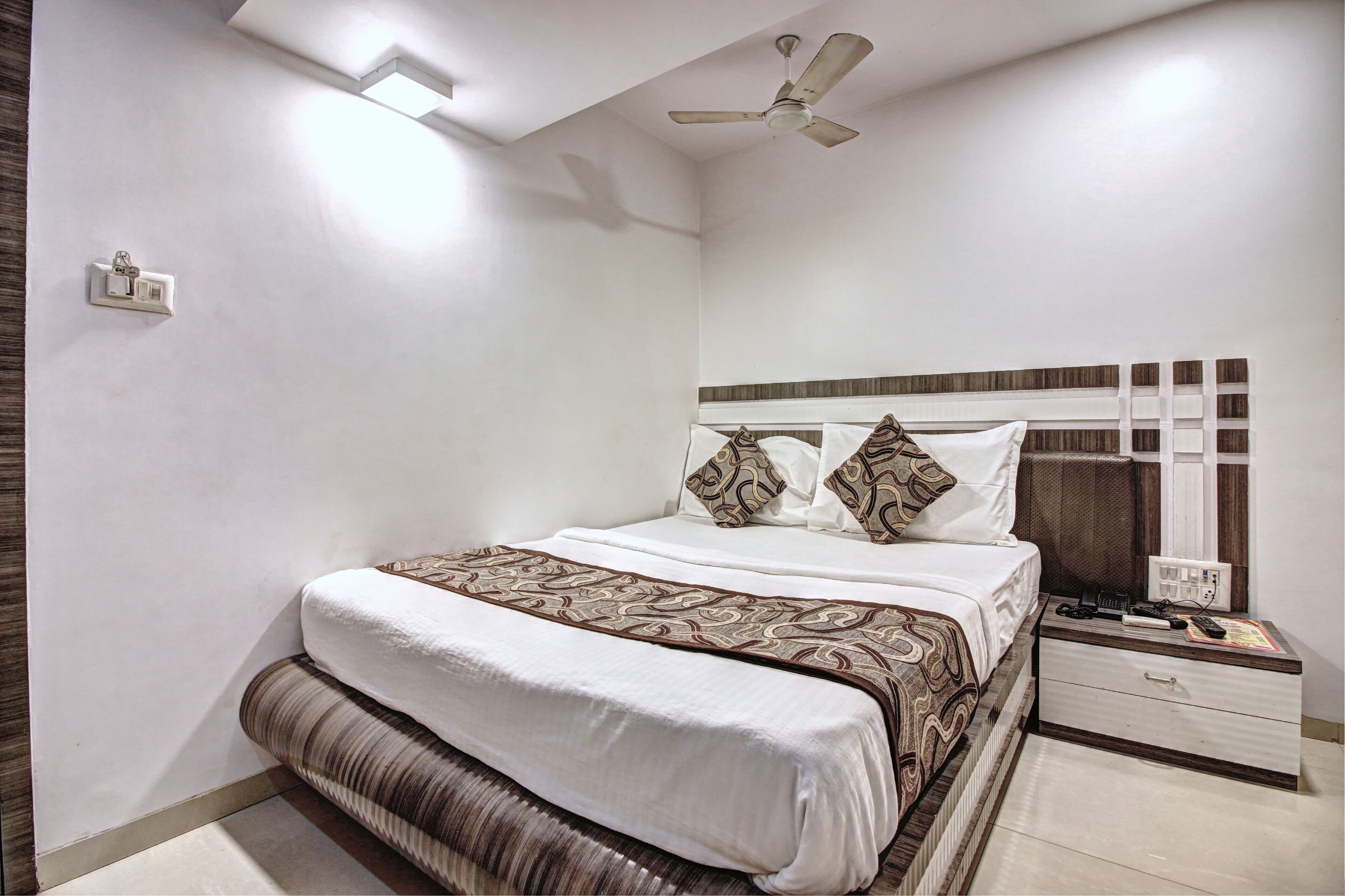 A neatly arranged bedroom with a bed, bedside table, and a ceiling fan.