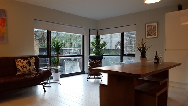 A modern living room with a wooden coffee table, a leather sofa, and large windows offering a view of the outside. - MetroStays - Temple Bar 5 (Dublin)