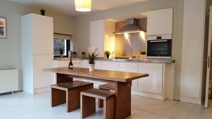 A modern kitchen with a wooden dining table and benches, white cabinetry, and a Bosch oven. - MetroStays - Temple Bar 5 (Dublin)
