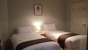 A hotel room with two single beds, a nightstand with a lamp, a framed picture on the wall, and a door. - MetroStays - Temple Bar 5 (Dublin)