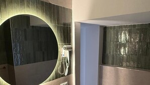 A bathroom with a round mirror, a sink with a modern faucet, a handheld showerhead, and a toilet. - Paraiso del Mar (Nerja)