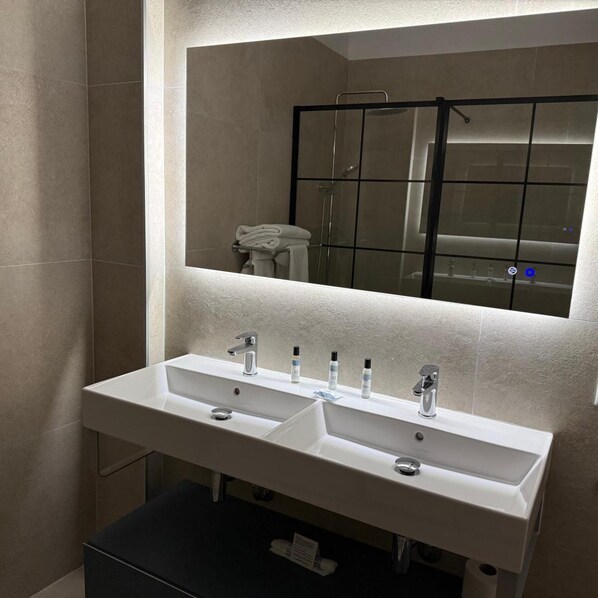 Un baño moderno con lavamanos doble, un espejo grande y cabina de ducha.