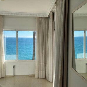 A room with a large window overlooking the sea, white curtains, and a large mirror. - Paraiso del Mar (Nerja)
