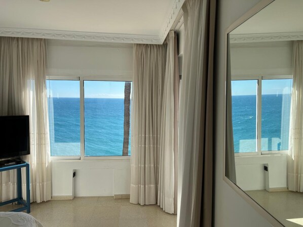 A hotel room with a large window, a flat-screen TV, and a mirror. - Paraiso del Mar (Nerja)