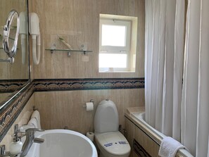 A bathroom with a bathtub, toilet, sink, and a window. - Paraiso del Mar (Nerja)