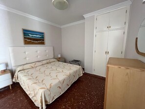 A bedroom with a bed, a wardrobe, a nightstand, a lamp, and a painting on the wall. - Paraiso del Mar (Nerja)