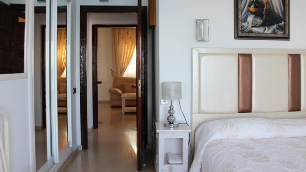 A hotel room with a bed, bedside table, lamp, and a painting on the wall. - Paraiso del Mar (Nerja)