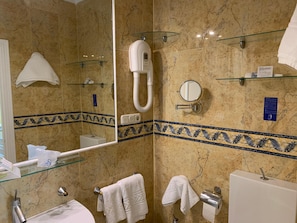 Baño con cabina de ducha de vidrio, ducha de mano, toallero, inodoro y espejo.