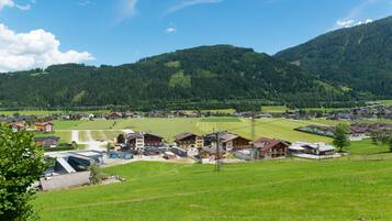 Ein ländliches Dorf mit Häusern, einem kleinen Gebäude mit Satteldach und einem grünen Feld.
