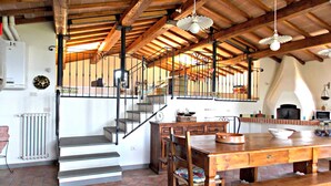 Une cuisine rustique avec une table en bois, un banc et un escalier menant à un niveau supérieur.