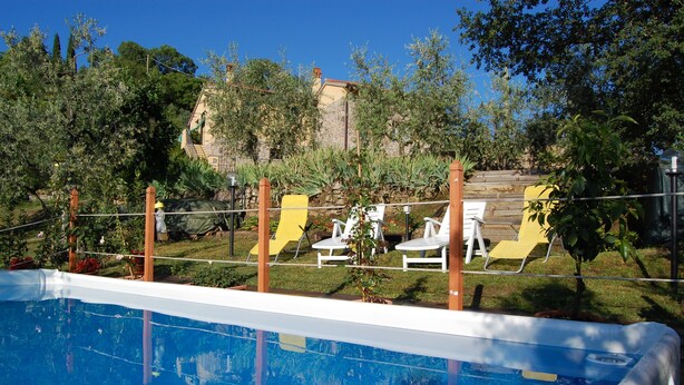 Une piscine entourée de chaises longues blanches, avec un bâtiment en pierre en arrière-plan.